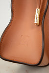 Close-up of a brown leather handbag with a gold clasp on a light background