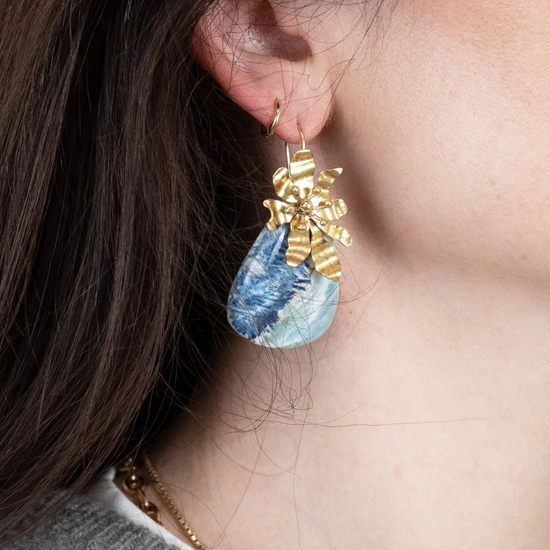 Close-up of a person wearing gold and blue earrings.