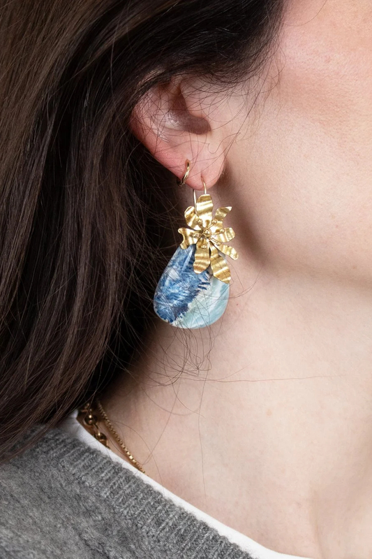 Close-up of a person wearing gold and blue earrings.