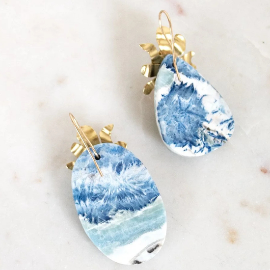 Blue and white marbled earrings with gold accents on a light background