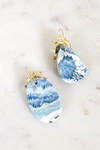 Blue and white marbled earrings with gold accents on a light background