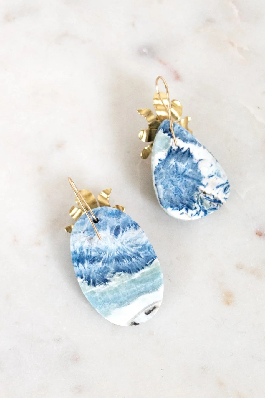 Blue and white marbled earrings with gold accents on a light background