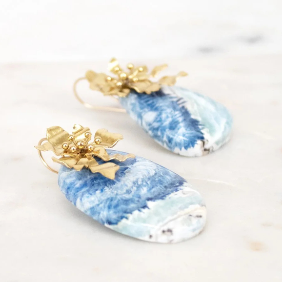 Blue and white marbled earrings with gold accents on a light background