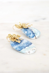 Blue and white marbled earrings with gold accents on a light background