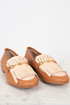 Pair of tan and beige loafers with tassel details on a light background