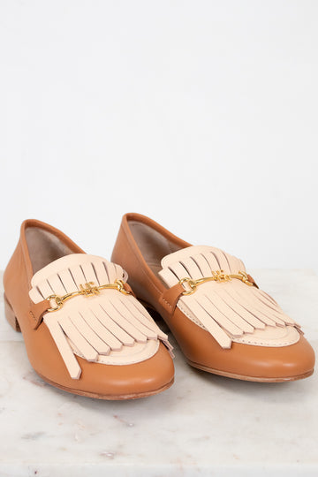 Pair of tan and beige loafers with tassel details on a light background