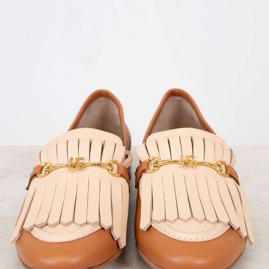 Pair of tan loafers with beige fringe on a light background