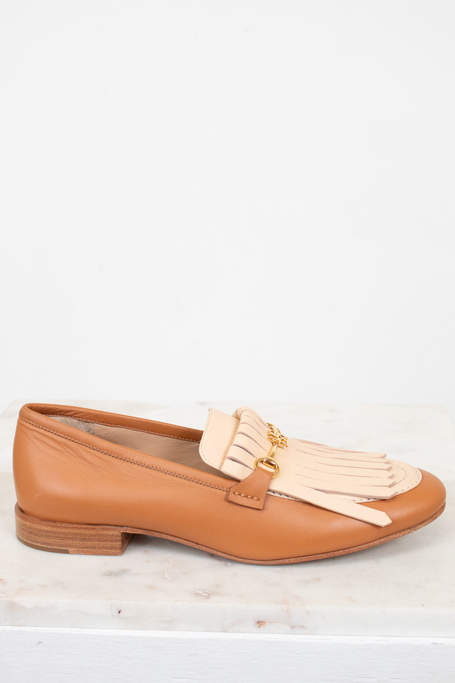 Tan loafer with beige tassel on a white background