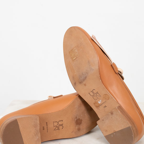 Close-up of brown bottom sole of shoes with visible brand logo on a white background