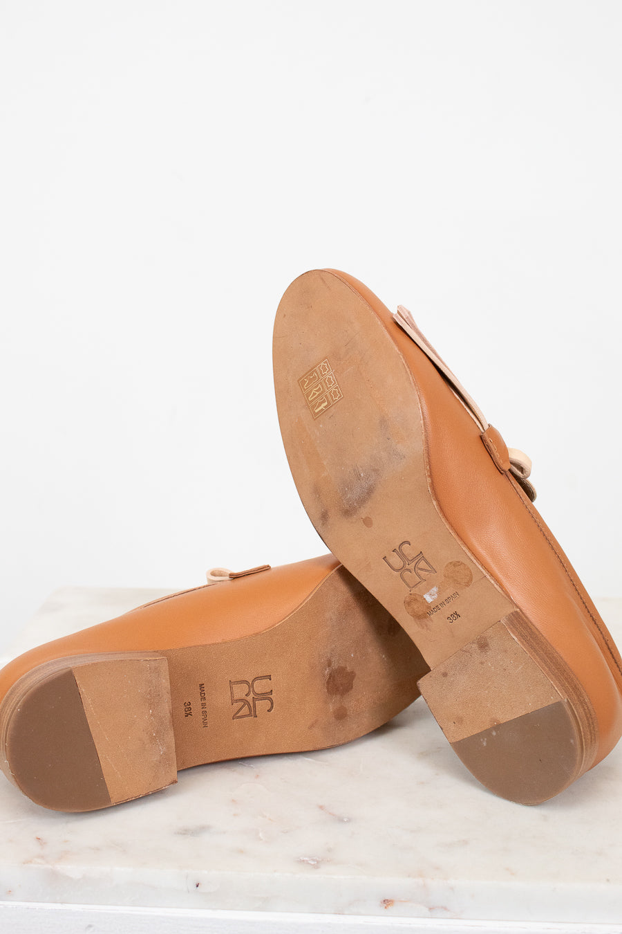 Close-up of brown bottom sole of shoes with visible brand logo on a white background