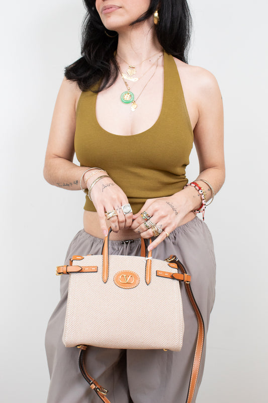Woman holding a beige handbag with brown straps against a white background