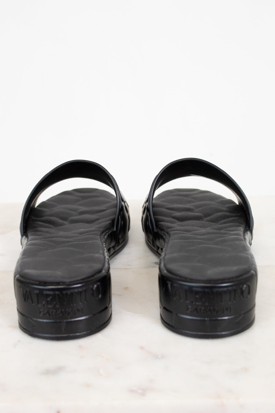 Black sandals with a Valentino brand logo on a white background