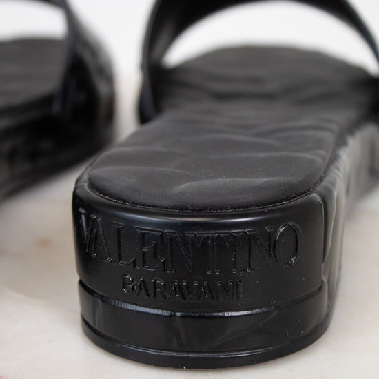 Black sandals with a Valentino brand logo on a white background