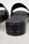 Black sandals with a Valentino brand logo on a white background