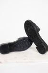Black sandals with floral details and a Valentino brand logo on a white background