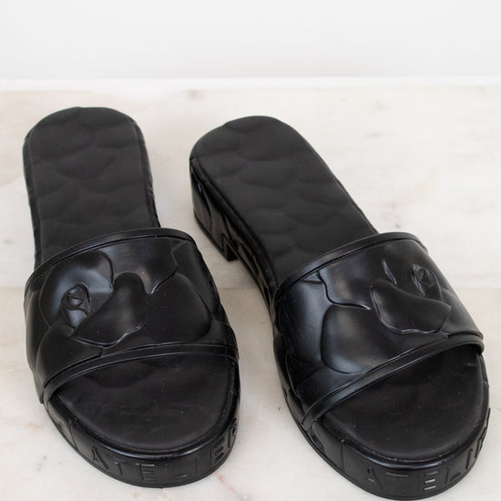Pair of black slides on a light marble background