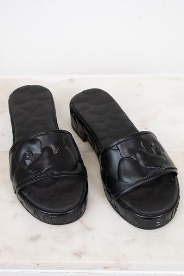 Pair of black slides on a light marble background