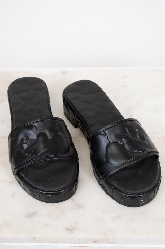 Pair of black slides on a light marble background
