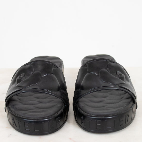 Pair of black slides on a white marble surface