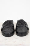 Pair of black slides on a white marble surface