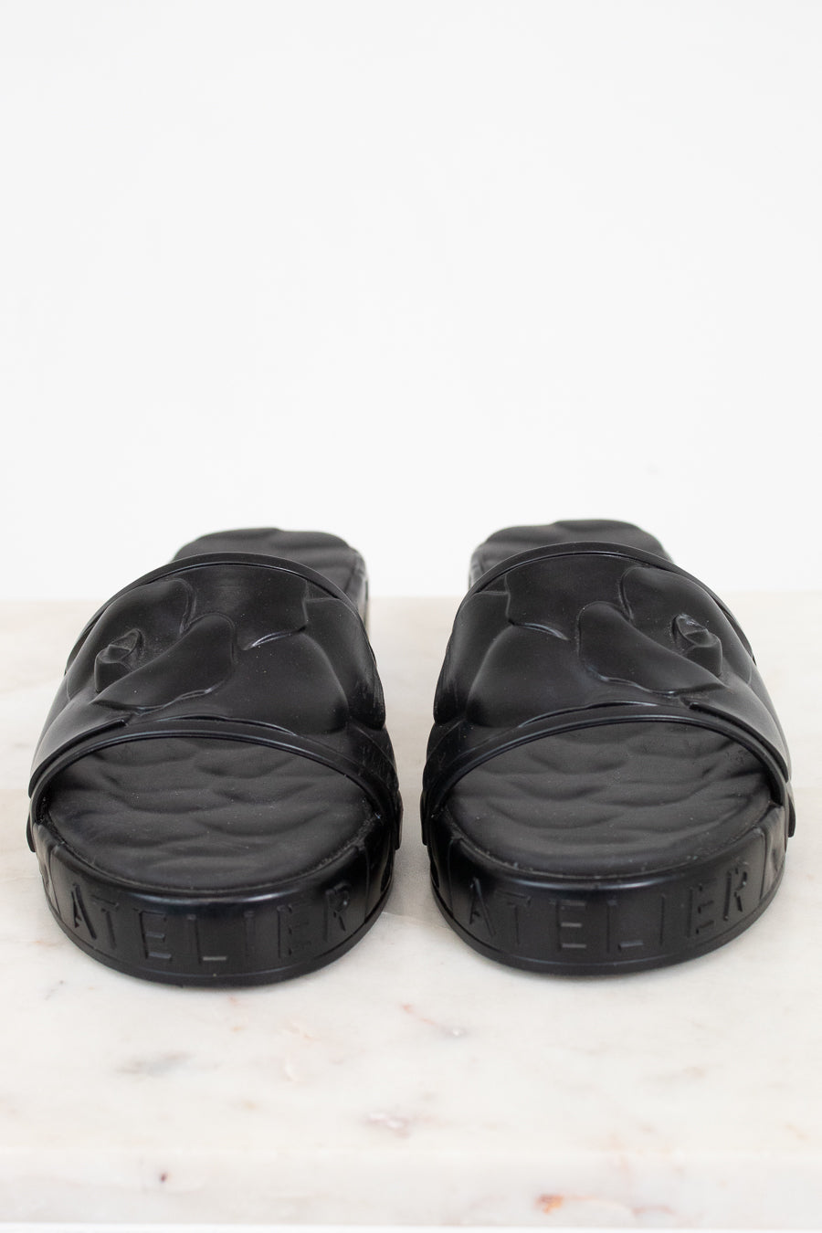Pair of black slides on a white marble surface