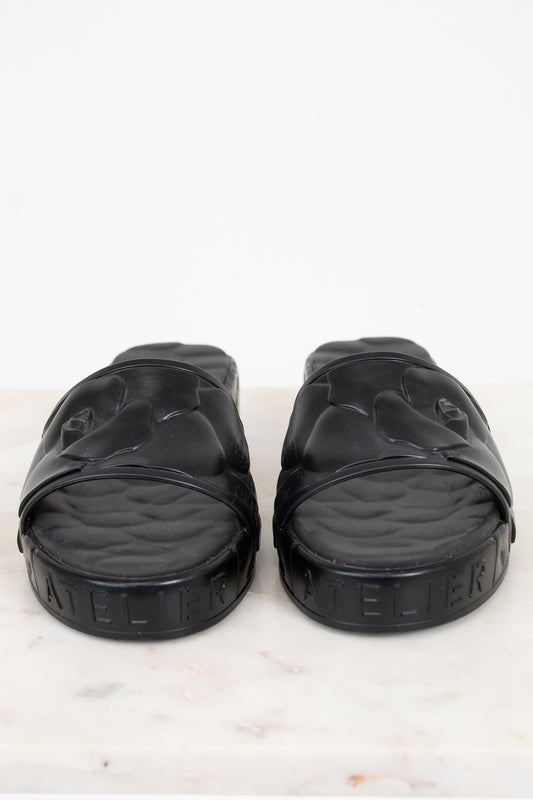 Pair of black slides on a white marble surface