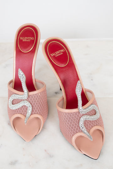 Pink high-heeled shoes with rhinestone snake detail on a white background with Valentino logo.
