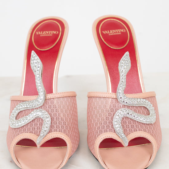 Pink high-heeled shoes with decorative elements on a light gray background
