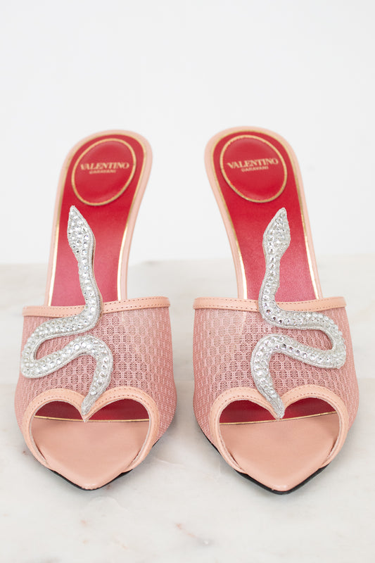 Pink high-heeled shoes with decorative elements on a light gray background