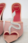 Pink high-heeled shoes with silver snake design on a light background