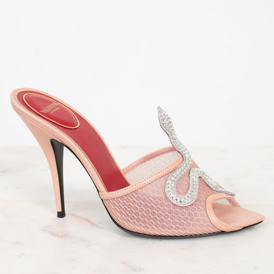 Pink high-heeled shoe with a decorative strap on a white background