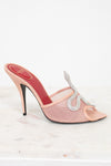 Pink high-heeled shoe with a decorative strap on a white background