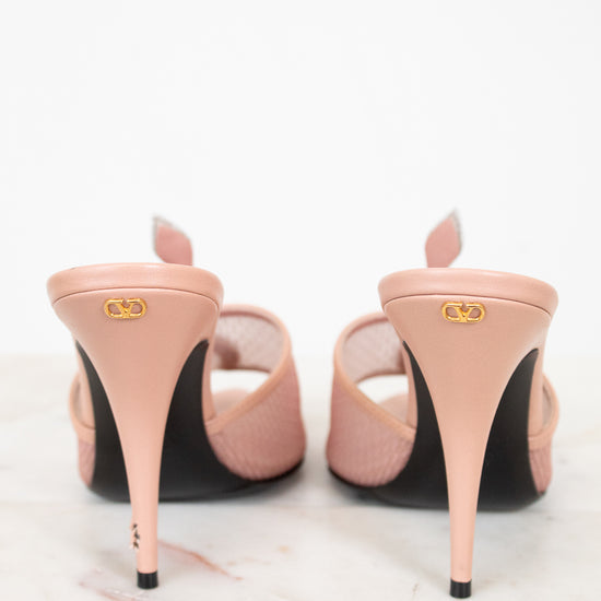Pair of pink high-heeled shoes with black soles on a white background