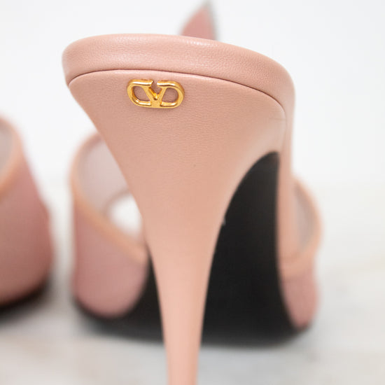 Pink high-heeled shoes with a gold logo on a light background