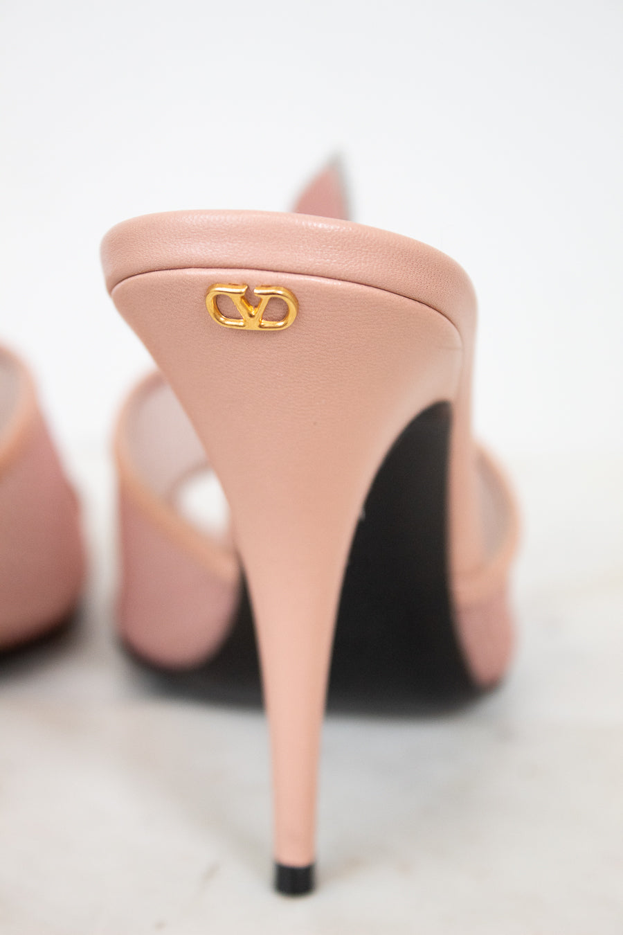 Pink high-heeled shoes with a gold logo on a light background