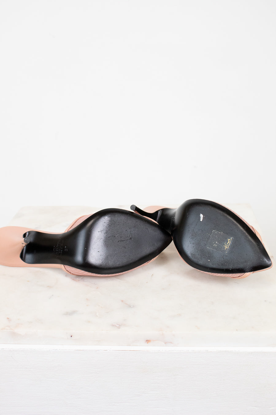 Black soles of high heeled shoes on a white background