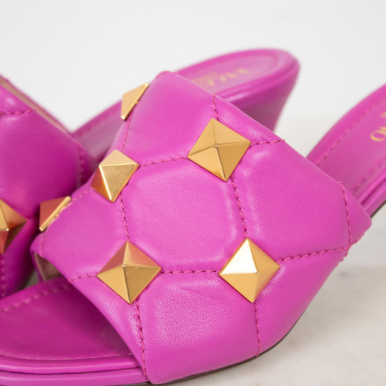 Pink sandals with gold studs on a light background