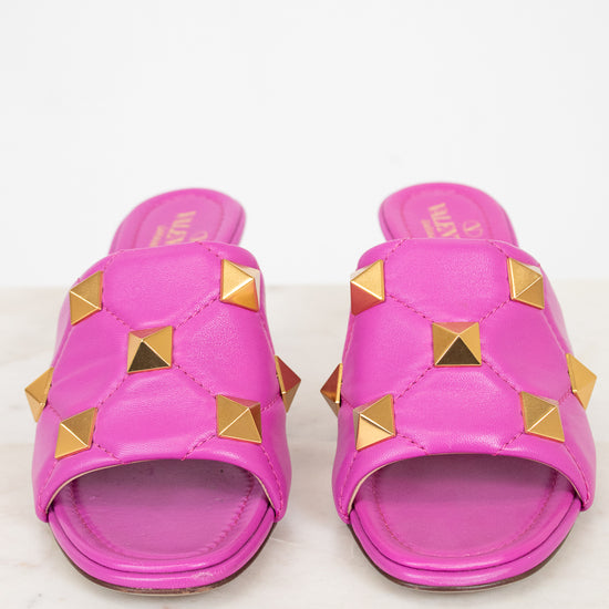 Pair of pink heeled sandals with gold studs on a white background