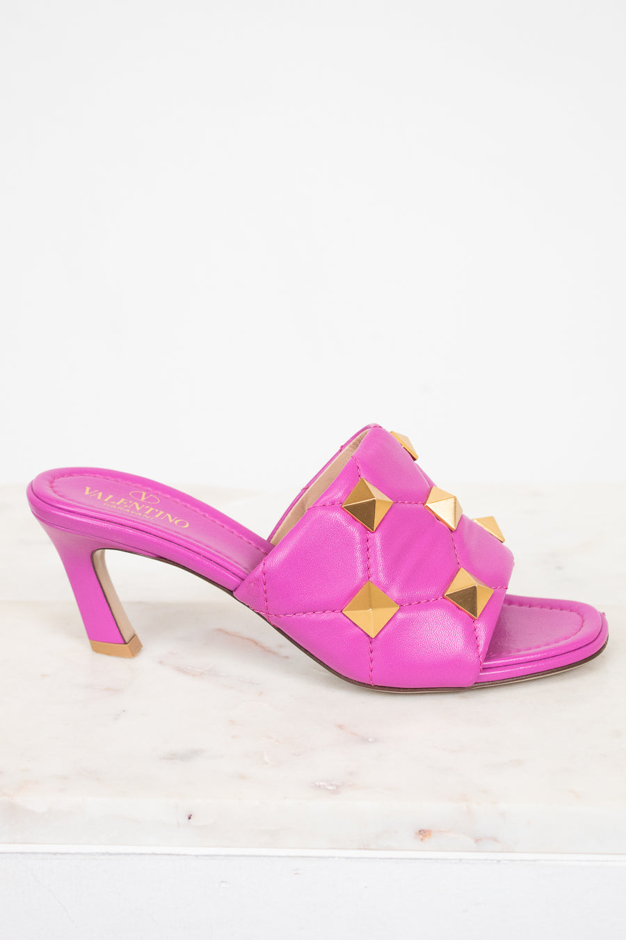 Pink heeled sandal with gold accents on a white background