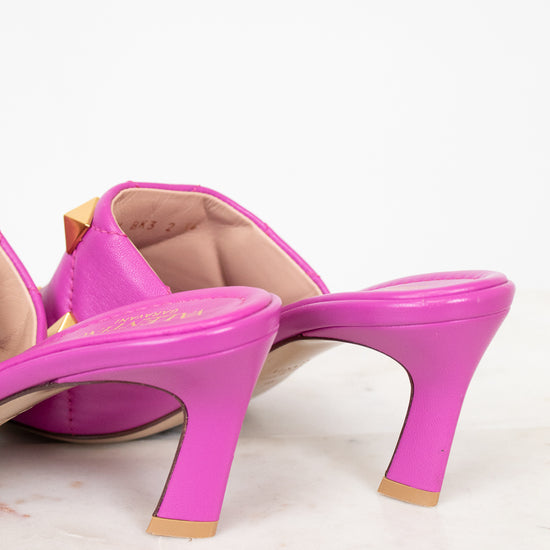 Pink heeled sandals with gold studs on a light background