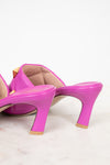 Pink heeled sandals with gold studs on a light background