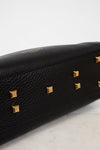 Black handbag with gold studs on a light gray background