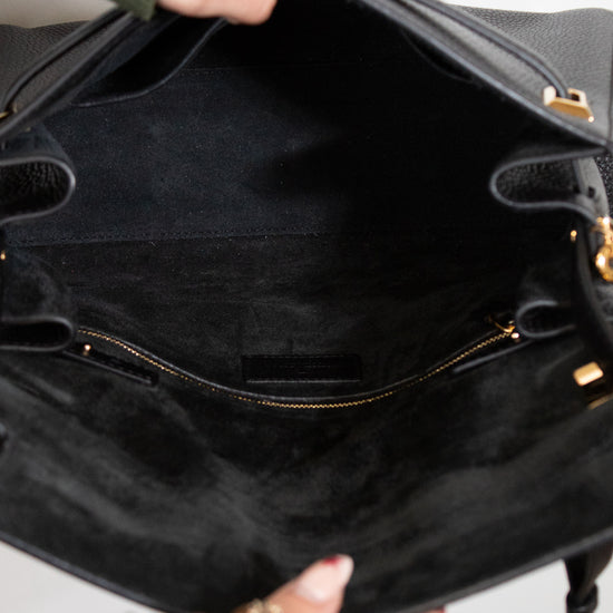 Close-up of a person holding a black handbag with gold accents.