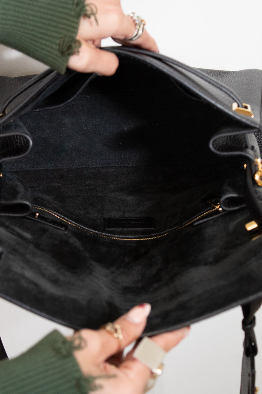 Close-up of a person holding a black handbag with gold accents.