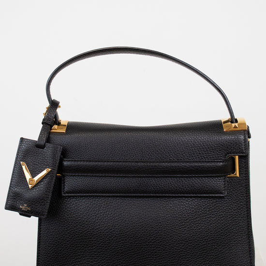 Black handbag with gold accents on a light background