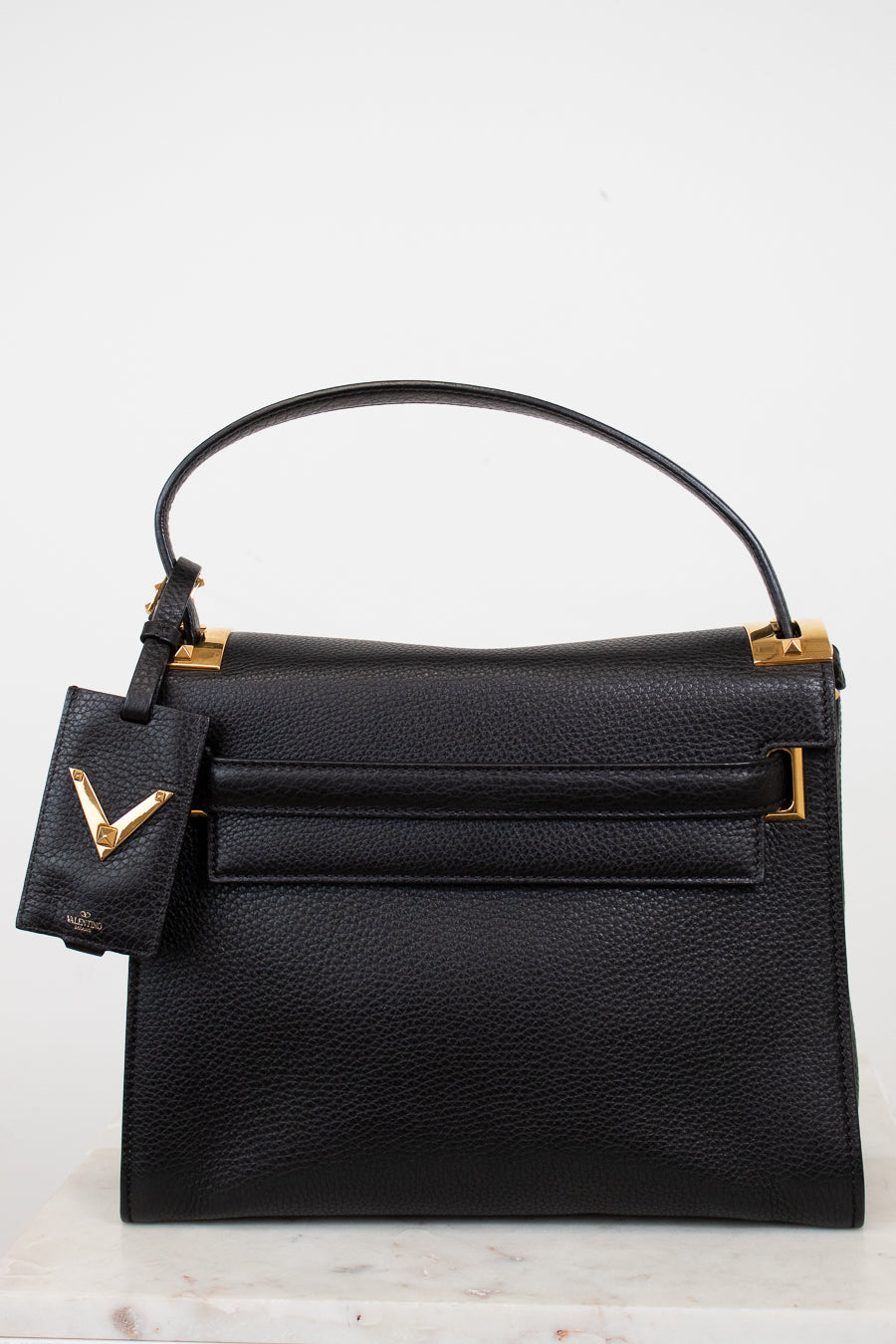 Black handbag with gold accents on a light background