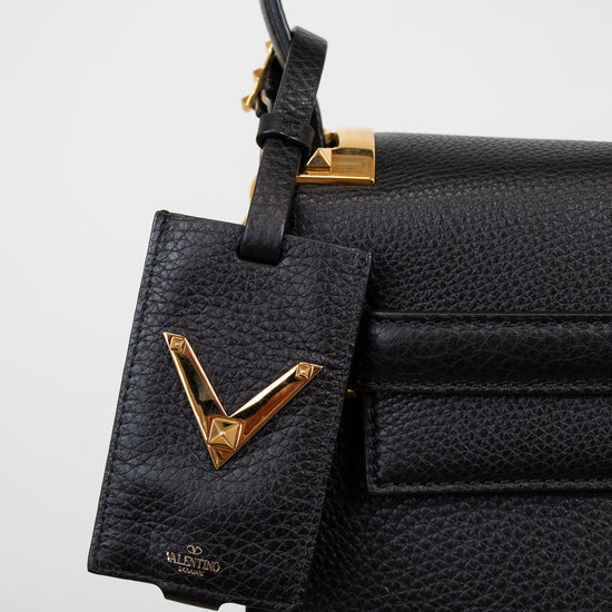 Black leather handbag with gold accents on a white background