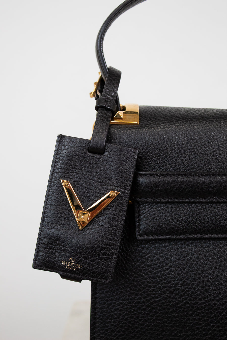 Black leather handbag with gold accents on a white background