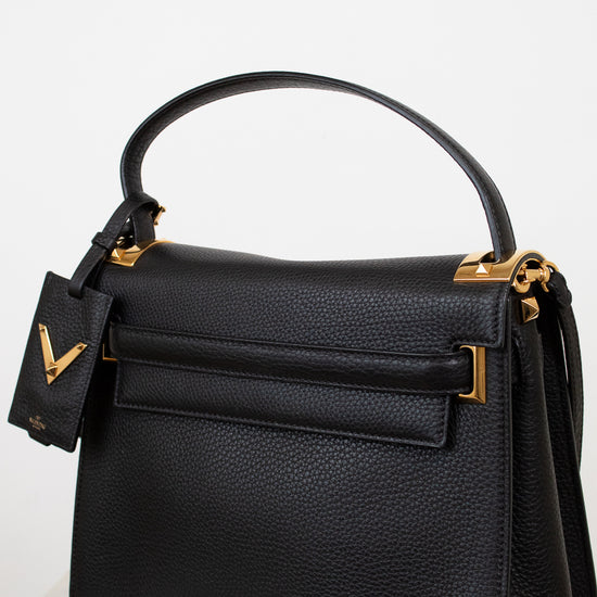 Black handbag with gold accents on a light gray background