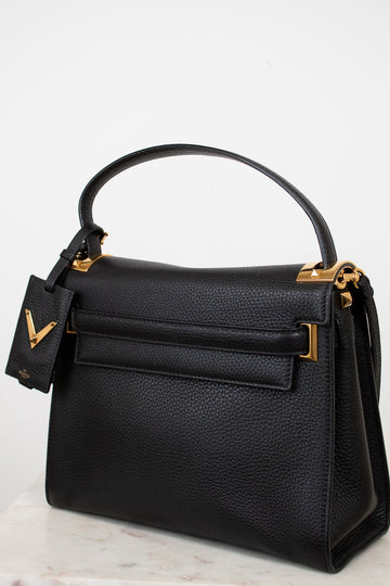 Black handbag with gold accents on a light gray background
